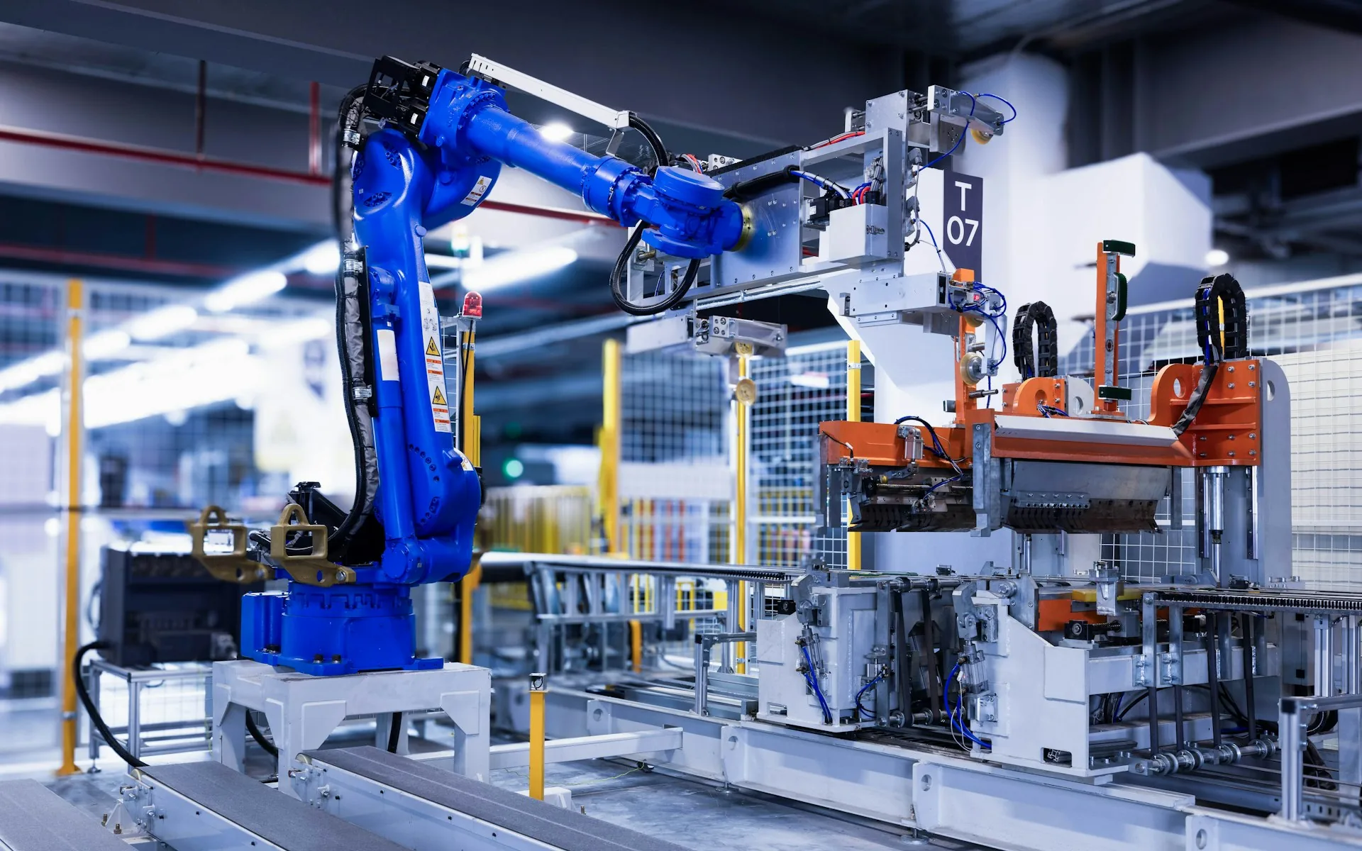A blue industrial robotic arm operating on a factory floor, representing AI agents in business automation
