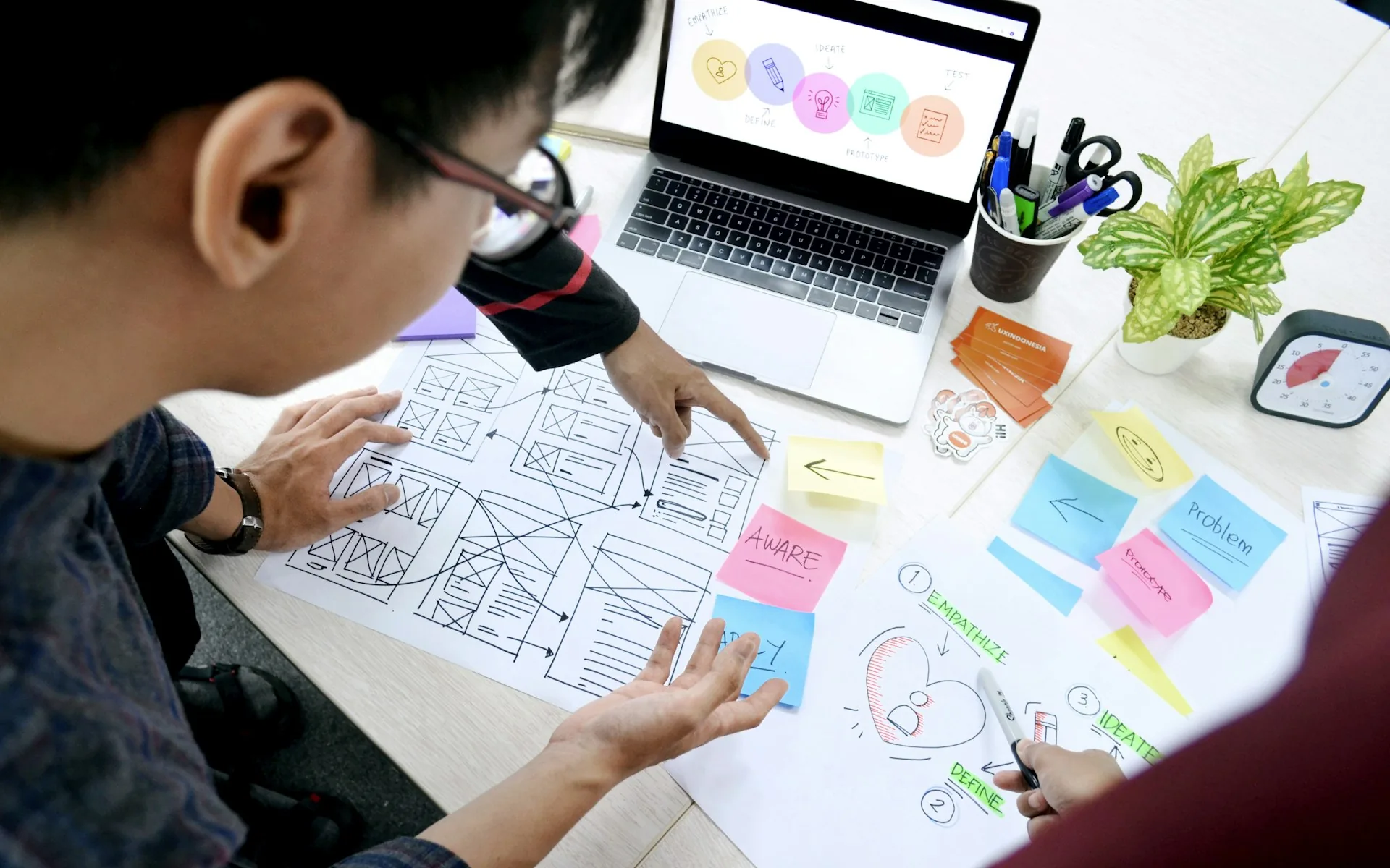 A designer sketching wireframes at a desk with a laptop, representing custom design versus theme-based websites